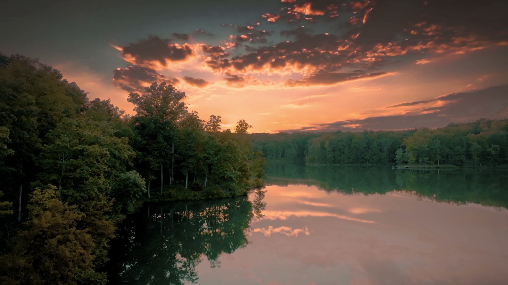 A lake at sunset inside the forest, seen from the air