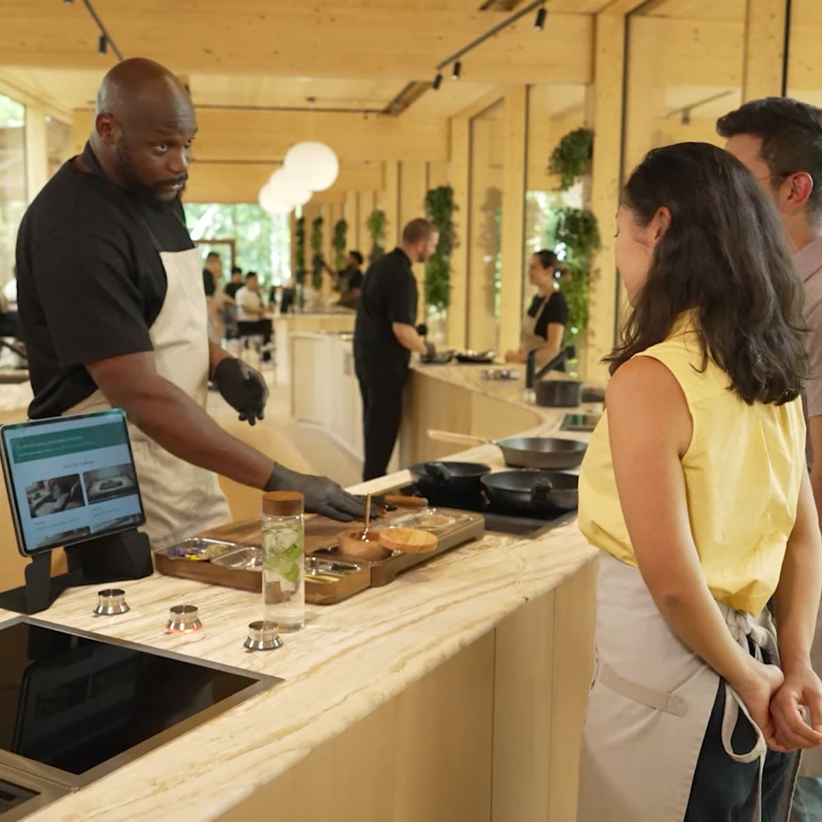 A Head Chef at the pass, walking two members through the plate