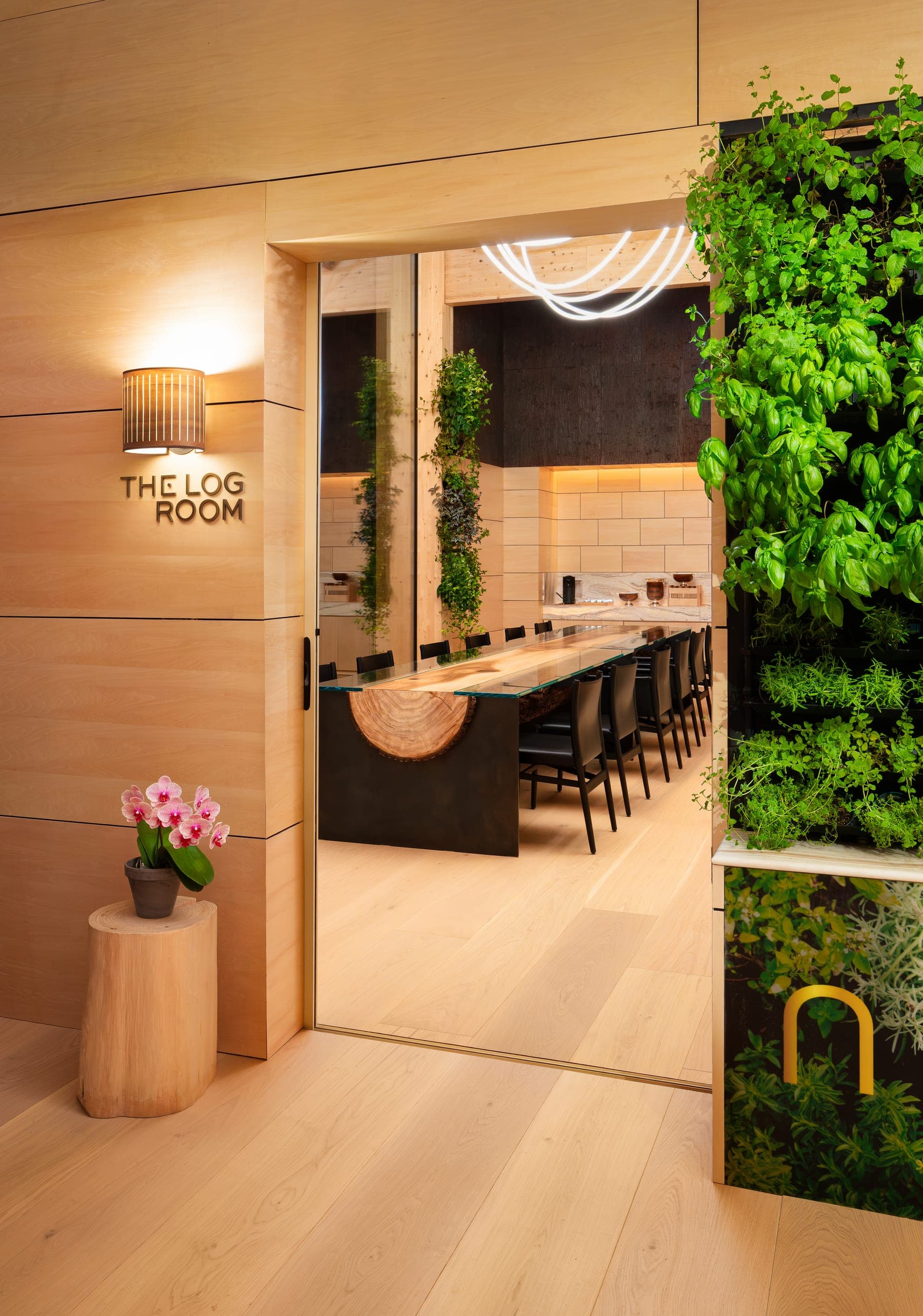 The Log Room — its name on the timber wall at the door, the long table under the light ribbon beyond