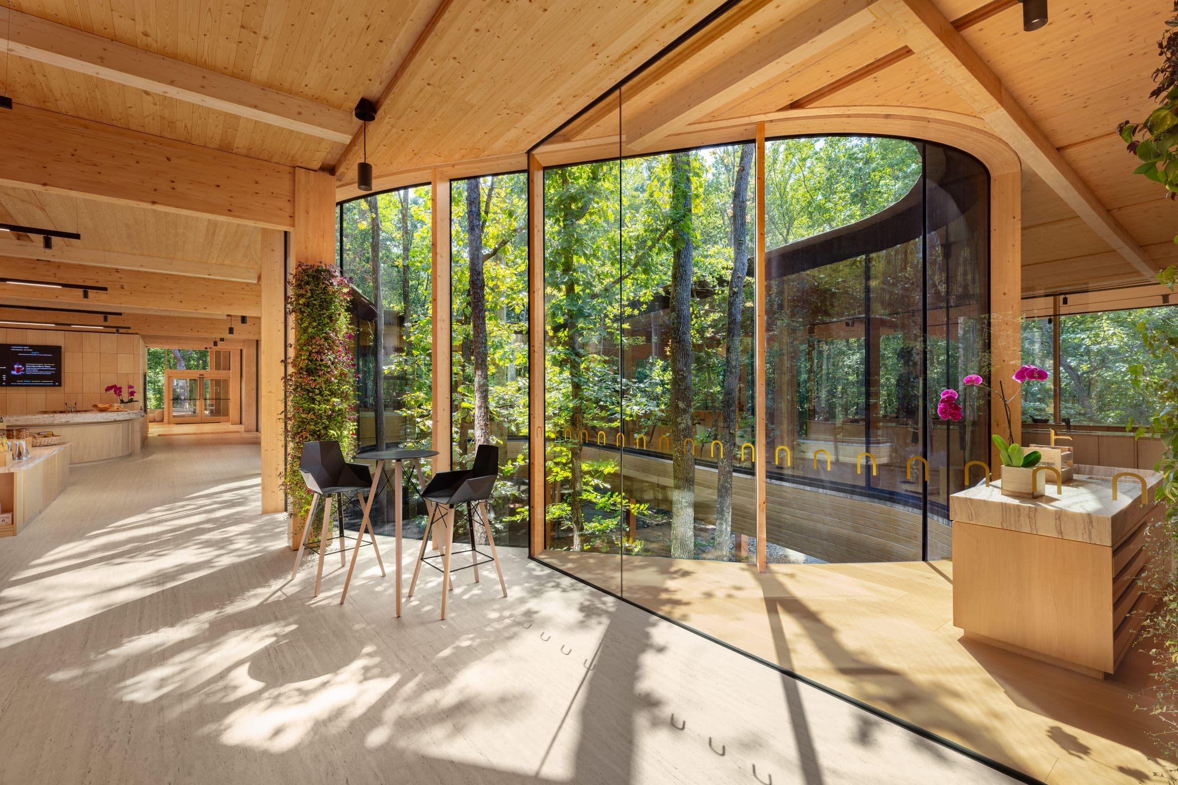 Inside the Nest — a high table and two stools at the curved glass, the courtyard's trees rising through the middle of the building