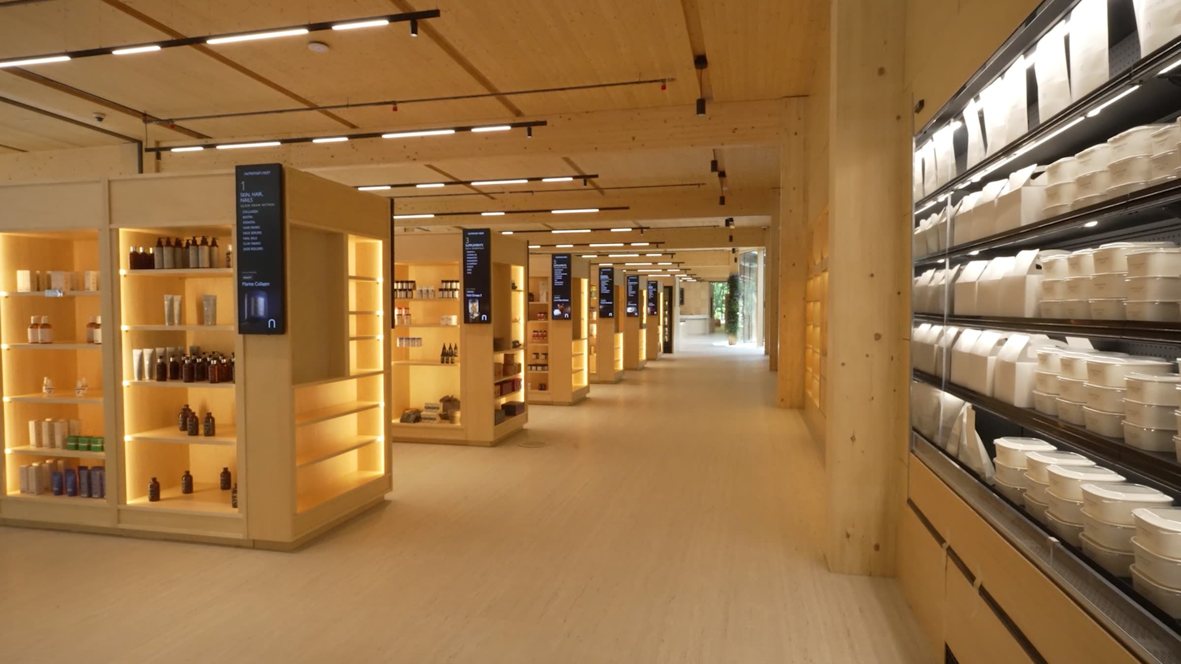 The Functional Market — the supplement aisle, lit timber cases and the refrigerated wall